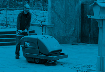 un travailleur utilisant la balayeuse de plancher extérieure Tennant pour nettoyer les établissements